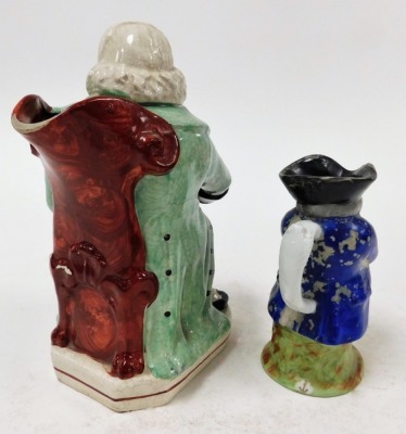 Two Staffordshire character jugs, to include a large Staffordshire potters character jug, of a seated gentleman in green outcoat, 23cm high, and another porcelain character jug, 15cm high. (2) - 2