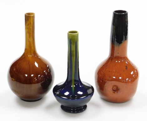 Three Studio Pottery stem vases, the orange fluted example marked Belgium 22cm high, another on a blue and green ground numbered 285 16cm high, and a brown flambe type example, in K Linthorpe style, unmarked, 22cm high. (3)