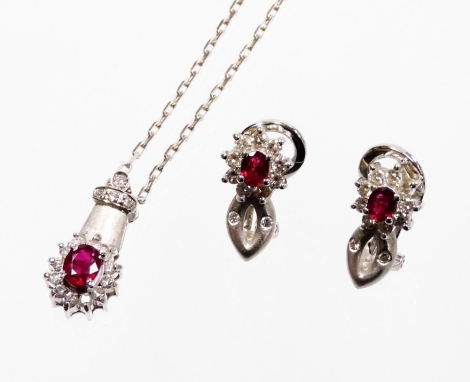 An 18ct white gold ruby and diamond jewellery suite, comprising earrings and necklace, each with brushed design loop, with a floral cluster with central ruby surrounded by tiny diamonds, the earrings with clip on backs, 1.8cm high, 4.9g, together with a m