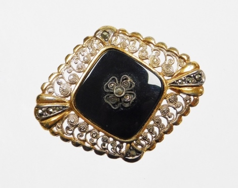 An Art Deco style marcasite and black agate set brooch, formed as a diamond with scroll detailing with some gold and silver plating, marked to reverse sterling, 4cm wide.