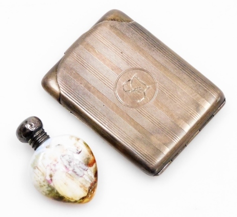 A George V silver card case, with engine turned decoration and central circular shield with initials DS, Birmingham 1923, together with a silver topped porcelain scent bottle (AF), 1¼oz gross. (2)