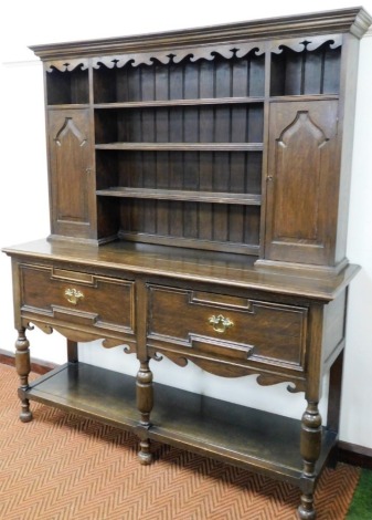 An oak mahogany dresser, the dresser top with carved fret above three shelves and two panelled doors, the base with two drawers above a pot board on turned supports and bun feet, 183cm high, 152cm wide, 50cm deep.