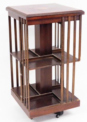 An Edwardian mahogany revolving bookcase, the top with fan parquetry inlay on two shelf section on castor supports, 100cm high, the top 52cm x 52cm. (AF)