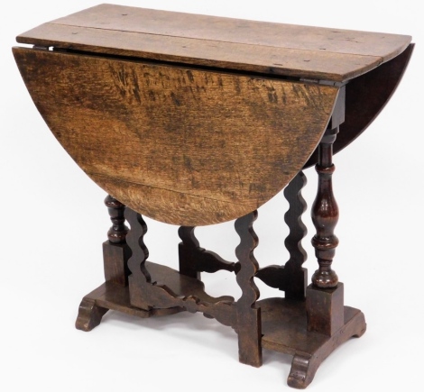 A 17thC oak drop leaf table, with twist design column pull out supports, and a two panelled top with pegs, 68cm high, 81cm wide, 36cm deep when closed.