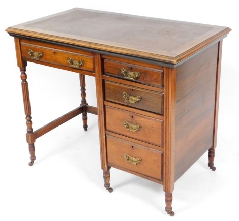 An Edwardian walnut console desk, with brown leather inset top above single drawer with four drawer bank on castors.