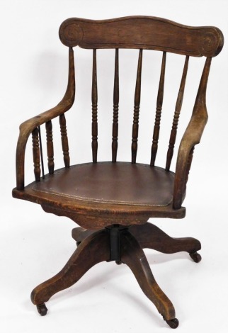 A 1920/30's oak swivel office chair, with scroll design back on splayed legs with castors and a drop in seat, 90cm high, 58cm wide, 46cm deep.