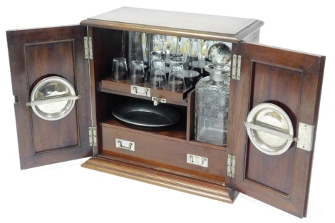 An Edwardian mahogany decanter box, with two cupboard doors opening to reveal fitted interior with glasses, ashtrays, and decanters, 36cm high, 36cm wide, 19cm deep.