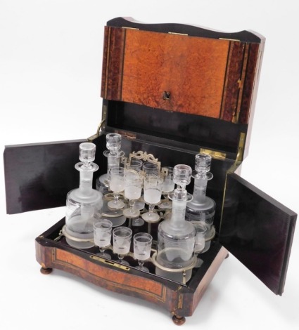 A Victorian Amboyna serpentine decanter box, with mottled top with a black finish shield, with mother of pearl inlay, with lift up lockable lid section opening to reveal four decanters and various sherry glasses, on bun feet, 27cm high, 32cm wide, 27cm de