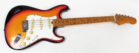 An electric guitar, with a turned wooden body with red outer border on white plate.