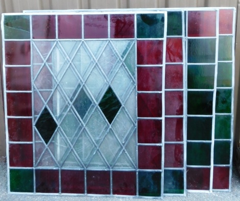 Four stained glass panels, each with red and green outer square border with diamond shaped centre, with two green glass section, the rest clear, 95cm x 85cm x 1cm. (AF)