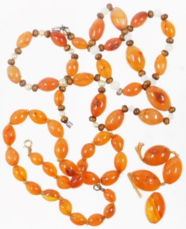 A group of orange hardstone beaded necklaces, to include one on string strand with yellow metal clasp stamped 9ct, 38cm long, a group of loose hardstone beads, and another with multi-stone pearl effect and wooden beads, 60cm long with chrome clasp.