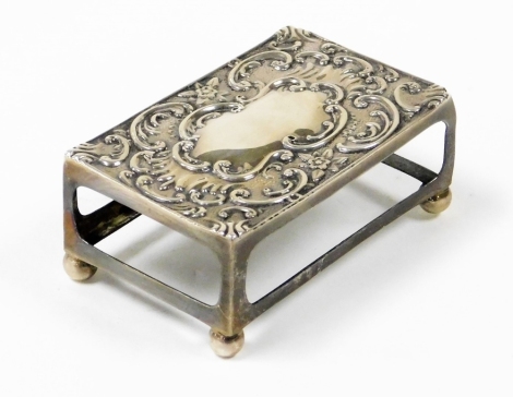 An Edward VII silver match box holder, with shell scroll detailed top on four bun feet, Birmingham 1902, ½oz.