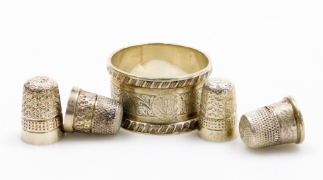 A silver napkin ring, with engine turned decoration baring the initials CHA, Chester 1899, together with three silver thimbles, 1½oz. (5).