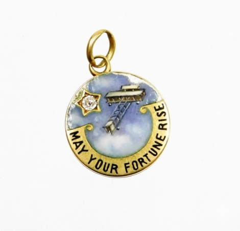 An early Edwardian bi-plane enamel pendant, with bi-plane detailing inscribed 'may your fortune rise' and set with tiny diamond, formed as a locket, yellow metal unmarked, 5.3g all in, 2cm wide.