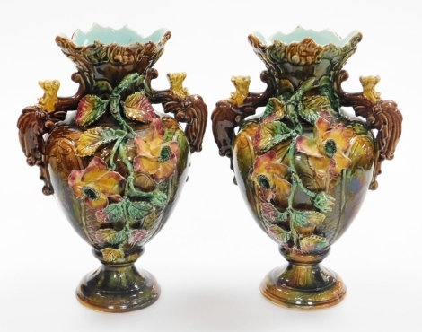 A pair of majolica Continental vases, each heavily encrusted with flowers, with flared rims, 31cm high.