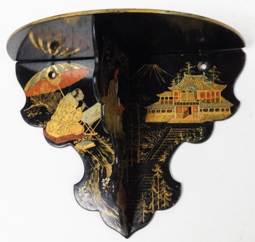 A Victorian papier mache wall shelf, on black ebonised base, with gilt decoration of Oriental figures and buildings, 18cm high, 25cm wide.