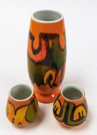 Three Poole vases, in orange ground with yellow and green, 23cm, 8cm, and 10cm high. (3)