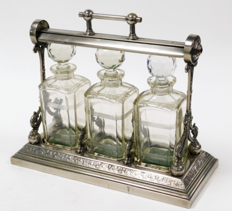 A silver plated Grinsell Patent tantalus, with three cut glass decanters, in case in neoclassical style, with vine and floral bordering, on a stepped base, 31cm high, 33cm wide, 16cm deep.