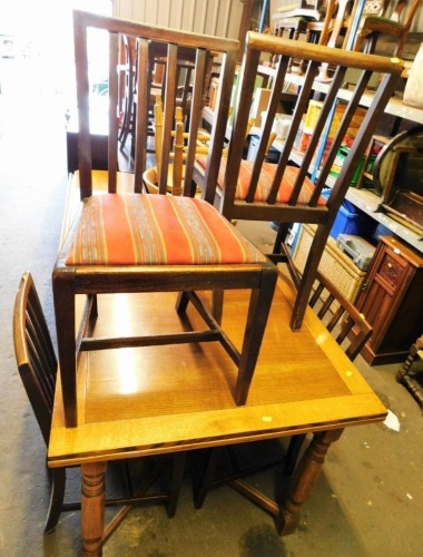 An oak square extending dining table and four mahogany chairs.