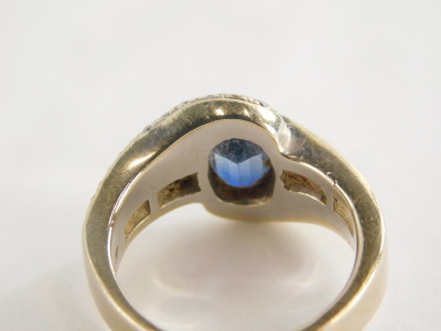 A sapphire and diamond dress ring, with oval sapphire in rub over setting, approx 1.43cts, white diamond set twist shoulders, with four round brilliant cut diamonds in tension setting, white metal, marked 750, ring size P½, 11.1g all in. - 2