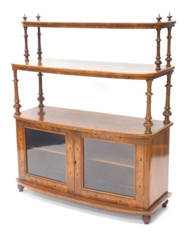 A Victorian figured walnut and marquetry whatnot cabinet, with two graduated bowfronted tiers, each on turned supports on finials, the base with two glazed doors, on bun feet, 125cm high, 106cm wide.