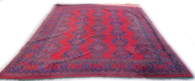 A large Turkish carpet, decorated with flowers, roundels, etc., in pale blue, navy and green, on a red ground with multiple borders, 440cm x 392cm.