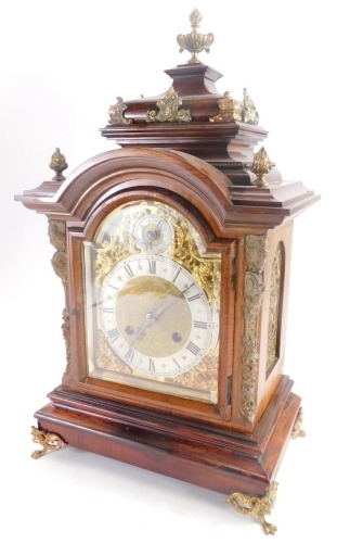 A late 19thC German rosewood mantel clock, with gilt metal mounts, the domed top embellished with flame finials, etc., above a arched brass dial with silvered chapter ring and pierced rococo cast spandrels flanked by caryatids, on paw feet, 48cm high.