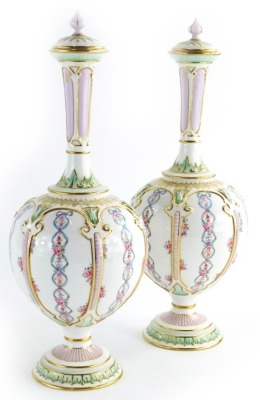 A pair of Royal Worcester porcelain bottle shaped vases and covers, each decorated with flowers, ribbons, etc., within compartments in Islamic style, on a domed foot, printed marks to underside, registration number 270100 numbered 1850, 33cm high.