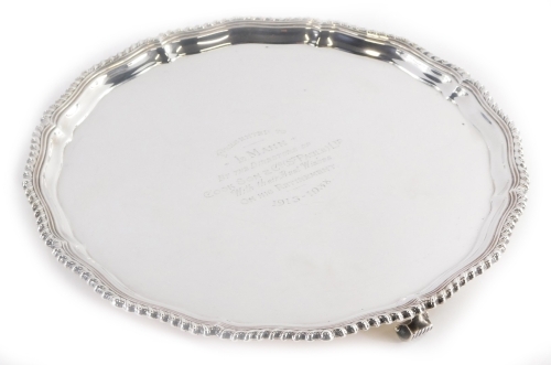 A George V silver salver, with a shaped and gadrooned border, the centre with the inscription 'Presented to L. Mann by the Directors of Cook Son and Co. (St Paul's) Ltd with Their Best Wishes on His Retirement 1913-1938', on three scroll feet, Birmingham