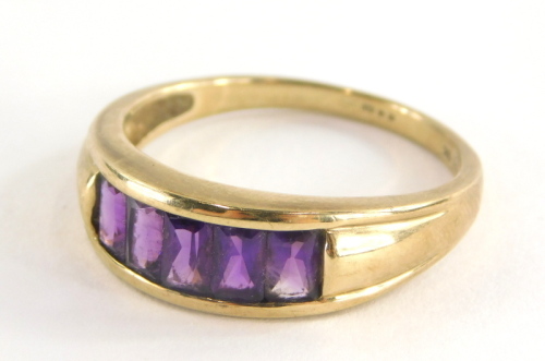A 9ct gold half hoop dress ring, with five rectangular cut amethysts, in a tension setting on yellow metal band stamped 375, ring size U½, 4.3g all in.