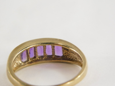 A 9ct gold half hoop dress ring, with five rectangular cut amethysts, in a tension setting on yellow metal band stamped 375, ring size U½, 4.3g all in. - 2