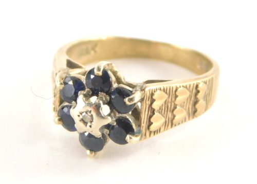 A 9ct gold cluster ring, with six sapphires and central illusions set tiny diamond and three layered heart shaped shoulders, ring size L½, 3g all in.