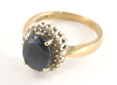 A 9ct gold sapphire and diamond dress ring, sapphire approx .25cts, the central oval cut sapphire surrounded by tiny diamonds, each in white gold setting on a yellow metal band, ring size P½, 4.6g all in.