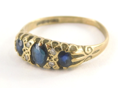 An 18ct gold sapphire and diamond gypsy ring, set with three oval cut sapphires and four tiny diamonds, on a misshapen band, ring size R, 2g all in.