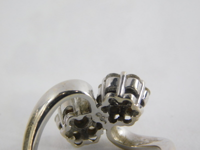An 18ct white gold diamond twist ring, with two floral cluster diamond sections, on twist detailing, each diamond approx 0.10cts, in a claw setting, marked 750, ring size O½, 5.g all in. - 2