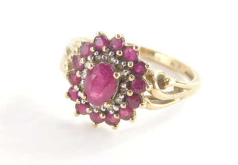 A 9ct gold cluster ring, with oval cut ruby in claw setting surrounded by cz stones and outer round brilliant cut rubies, on a two row twist design shoulders, ring size P½, marked QVC, 4.1g all in.