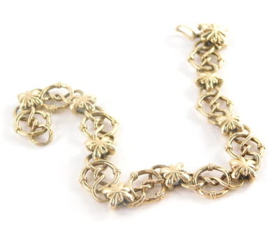 A 9ct gold bracelet, fancy link with elaborate loop and twist design with flower pendant brakes, and clasp to match, with safety clip, 22cm long, 23.3g.