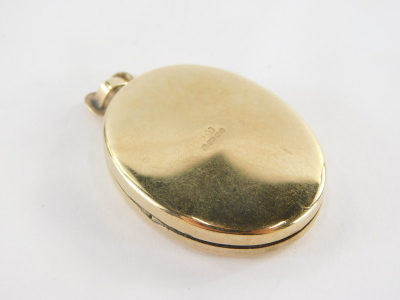 A 9ct gold oval pendant, the front with etched design of birds and flowers, opening to reveal two photograph section, 4cm high, 9.5g all in. - 2