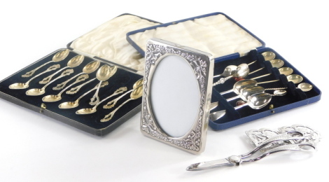 A collection of silver plated items, to include an early 20thC silver plated belt buckle, decorated with flowers, leaves, etc., a pair of grape scissors, the handles decorated with leaves, silver plated photograph frame, various spoons to include coffee b