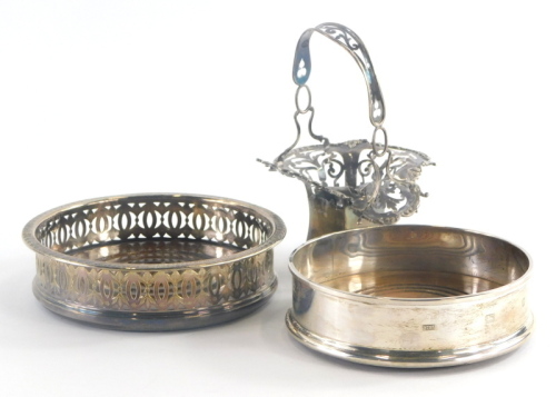 An Elizabeth II silver wine coaster, of plain form with turned wooden base, London 1990, a silver plated example with pierced decoration and a silver basket with pierced decoration. (AF, 3)