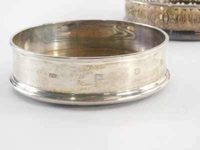 An Elizabeth II silver wine coaster, of plain form with turned wooden base, London 1990, a silver plated example with pierced decoration and a silver basket with pierced decoration. (AF, 3) - 2