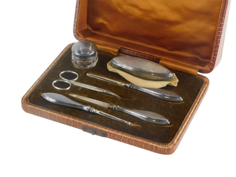 A George V silver mounted manicure set, with engine turned decoration, to include silver handled nail file, cuticle pusher, silver mounted and glass jar, etc., with engine turned decoration, Birmingham 1923, in a mock crocodile box.