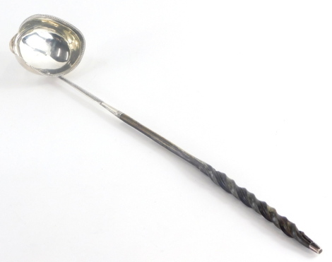 A 19thC ladle, with a silver coloured metal bowl and a beaded rim, initialled to handle R.C, marks indistinct to bottom of bowl, with a horn or whale bone twisted handle, 38cm long. (AF)