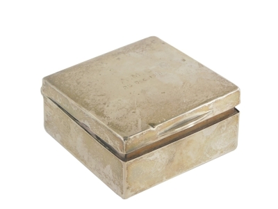 An early 20thC silver cigarette box, of square form, the top initialled AMC, 25th December 1912, the hinged lid revealing a treen interior, hallmarks rubbed, 8.5cm x 8.5cm x 4.5cm.