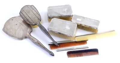 A silver dressing table set, with engine turned decoration comprising three brushes, a hair brush, mirror and various combs, some stamped sterling silver. (AF)