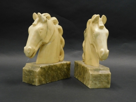 A pair of continental carved alabaster bookends, each modelled in the form of a horses head, 30cm high. (AF)