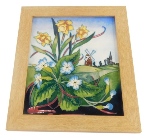 A Moorcroft pottery plaque, decorated with daffodils and blue flowers, with a windmill in the background, framed, limited edition number 26/100, signed by the artist, 31cm x 27cm overall.