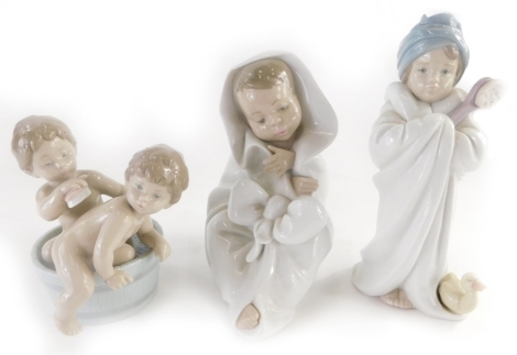 Three Spanish porcelain figures, a Lladro figure of a child with a brush, and a duckling, a figure of two children bathing in a barrel, and a Nao figure of a child. (3)