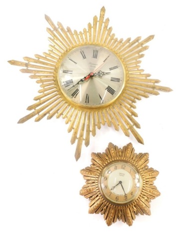 Two sunburst wall clocks, in silk plastic and silk metal cases.