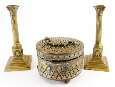 A pair of 19thC brass Corinthian column candlesticks, on a stepped base, 23cm high, (AF), and an eastern brass box, with pierced decoration, the hinged lid revealing a vacant interior.